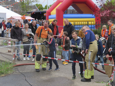902343 Afbeelding van leden van de vrijwillige brandweer die kinderen begeleiden bij het spuiten op een doel, onderdeel ...
